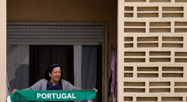 Una donna costretta in casa mostra una sciarpa del Portogallo