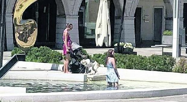 Mamma, figlia e cane: fa troppo caldo, tutti nella fontana. Solo il passeggino resta all'asciutto