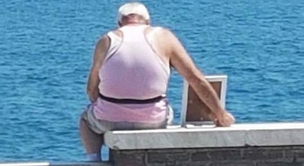 Anziano al mare con la foto della moglie morta: ecco la foto che commuove il web