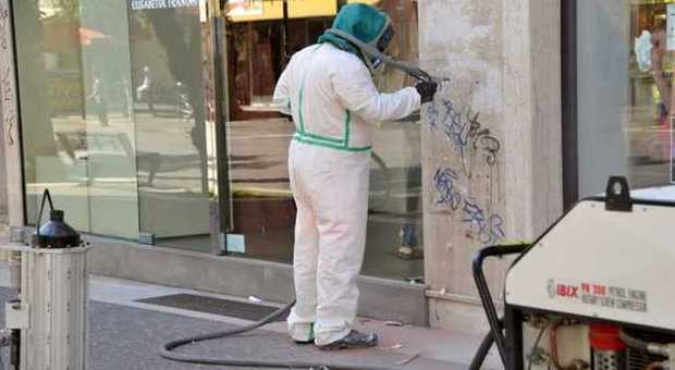 Un operaio pulisce un muro imbrattato