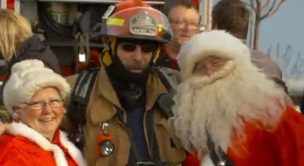 Babbo Natale eroe e la sua compagna accanto a un vigile del fuoco (Foto da video)