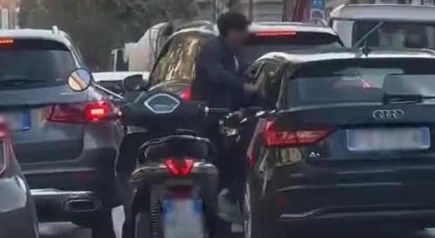 Scende dallo scooter e inizia a picchiare un automobilista a bordo di un'Audi. Il video è virale