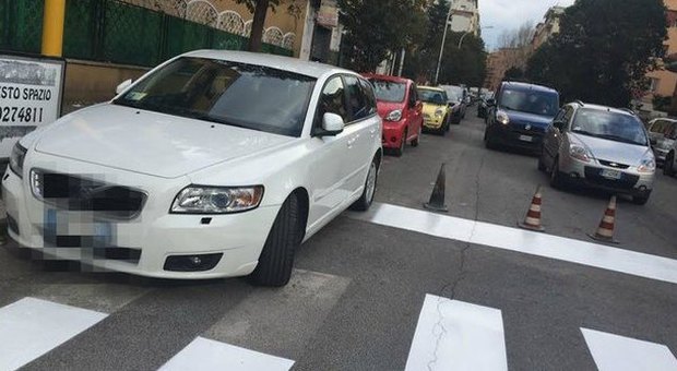 Roma, la macchina è in divieto di sosta: e le strisce pedonali si dipingono a metà