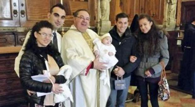 Padre Enzo Poiana tiene in braccio la piccola Kairyn: con lui ci sono i genitori e i padrini della piccola, la cui guarigione fa gridare