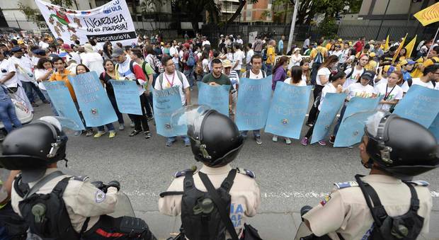 La polizia vigila i manifestanti che partecipano alla marcia indetta dall'opposizione a Caracas