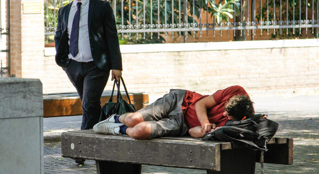 Un senzatetto che dorme su una panchina