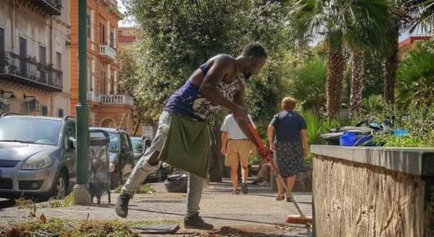 Uno dei ragazzi africani mentre pulisce una strada di Bagnoli