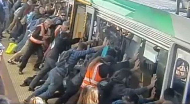 I passeggeri eroi scendono dal vagone per salvare l'uomo rimasto incastrato nel treno
