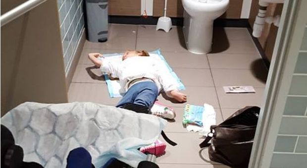 Mamma costretta a cambiare il figlio disabile nel pavimento della toilette, la foto diventa virale