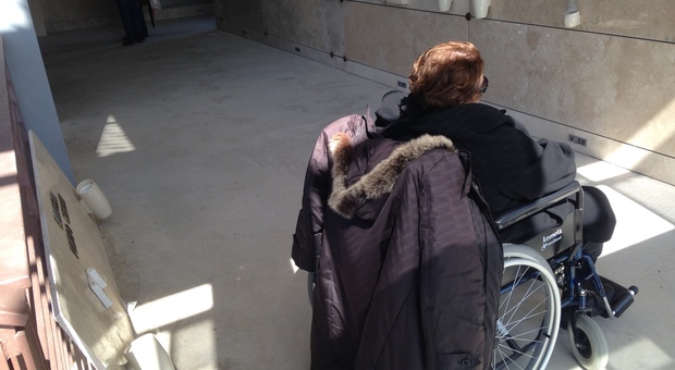 Una signora sulla sedia a rotelle ferma nel cimitero di Pianura