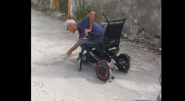 Anziano in carrozzina ripara buche