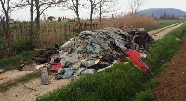 Foligno, mole di rifiuti tra vetro, sedili per auto, ferro e plastica abbandonata in campagna ostruisce una strada