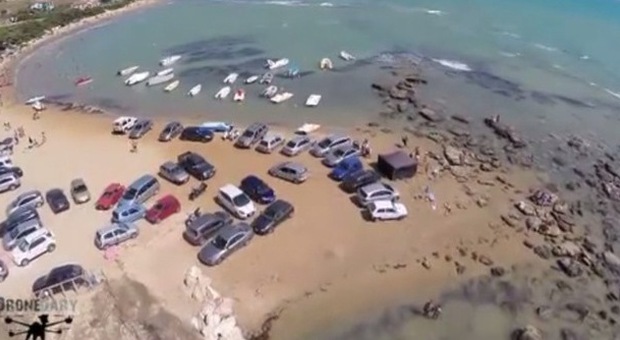 Auto parcheggiate fino al bagnasciuga sulla spiaggia in Sicilia