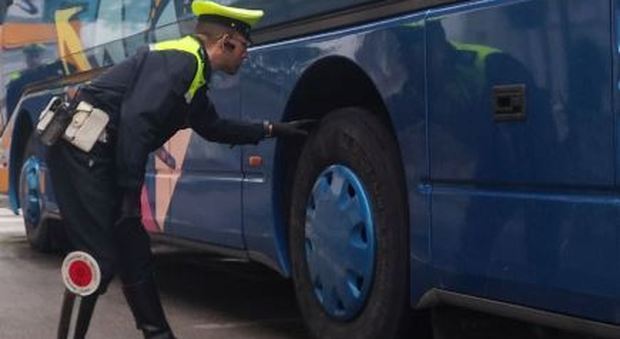 Un agente della Stradale controlla i pneumatici di un pullman