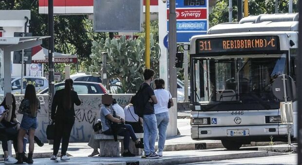 Persone alla fermata di un bus a Roma (foto Ansa)