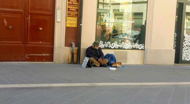 Mendicante con il cane in centro tra due negozi: nessuno interviene