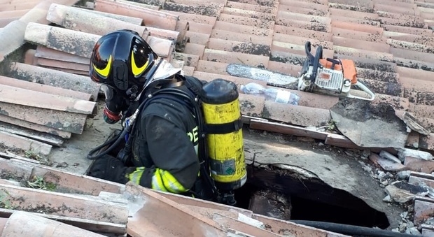 Un pompiere sul tetto di una delle villette danneggiate dal fuoco