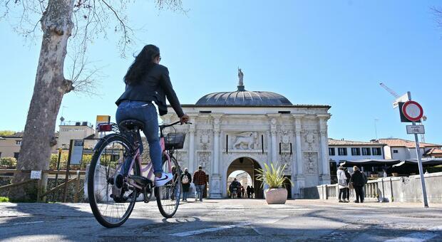 Pedoni e ciclisti davanti a Porta San Tomaso, uno dei monumenti simbolo di Treviso