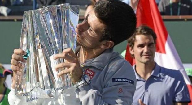 Novak Djokovic con il trofeo, alle sue spalle Federer (Ansa)