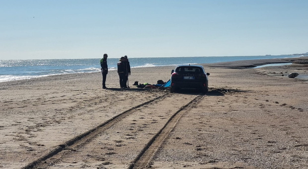 Con l'auto in spiaggia per scattare delle foto ma la macchina resta impantanata e dorme lì, i ...
