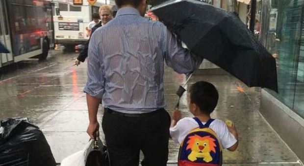 Il papà si bagna per proteggere il figlio dalla pioggia: in realtà sta facendo molto di più