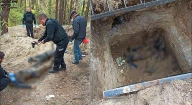 I cadaveri di due civili scoperti in una fossa comune, le foto choc: torturati e ammanettati insieme