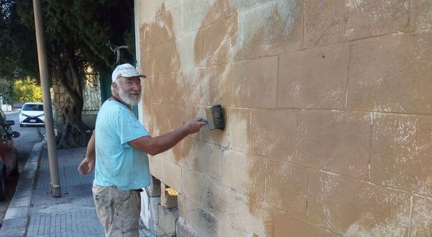 Vito Cisternino mentre pulisce il muro della scuola