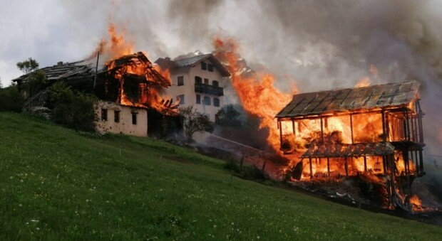 I fienili e le case in fiamme a Canazei, frazione di Colle Santa Lucia