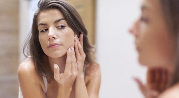 Una ragazza che controlla i risultati del peeling sulla pelle del volto