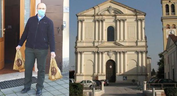 Don Claudio Bosa con le borse della spesa donata, e la chiesa di San Pietro a Camposampiero