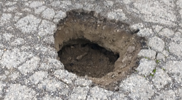 PERICOLO Il cratere che si è aperto per il cedimento sotto all'asfalto