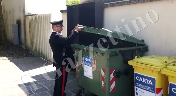 Un carabiniere mostra il cassonetto in cui è stato trovato il feto