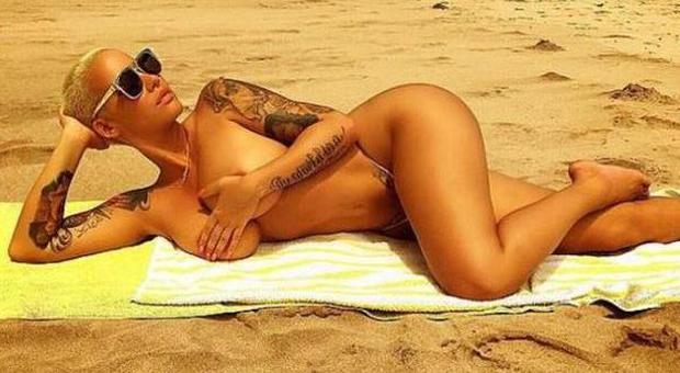 Amber Rose, topless e tanga minimal: tintarella quasi integrale sulla spiaggia