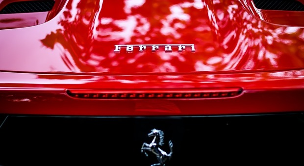 Il logo Ferrari dietro una supercar del cavallino