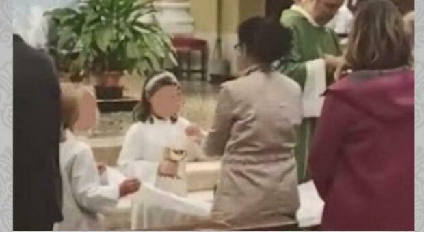 parroco fa distribuire l comunione a una bambina