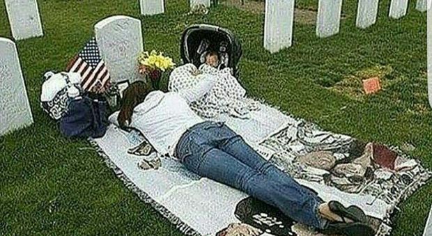 La moglie sdraiata con il suo bimbo sulla tomba del marito: la foto che commuove il web