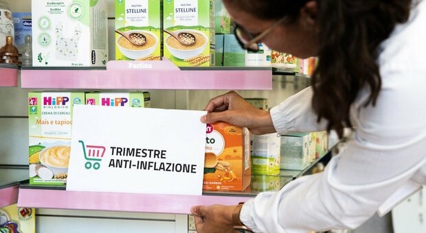Una farmacista sistema un cartello del trimestre anti-inflazione su alcuni prodotti