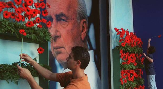 Un giovane mette dei fiori vicino a un ritratto di Rabin