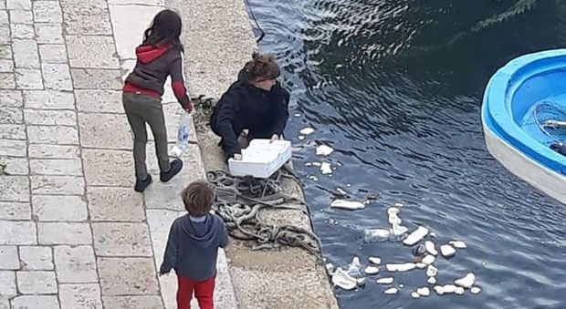 La donna e i bambinimentre raccolgono rifiuti dal mare