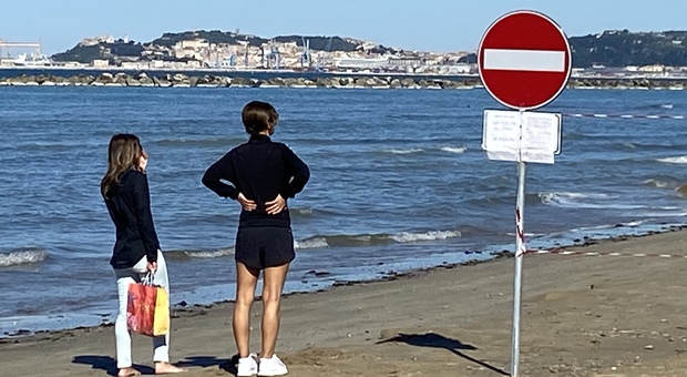 Il cartello che divide la spiaggia a Palombina: ad Ancona le passeggiate sono vietate, a Falconara sono consentite