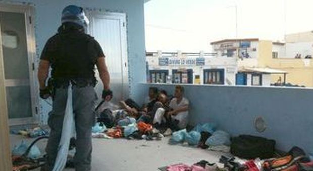 Un agente e alcuni tunisini dopo gli scontri (Elio Desideri - Ansa)