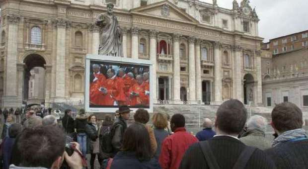 Visitors watch a mass at St. Peter's Basilica shown on a video monitor in Vatican (M. Sohn / Ap)
