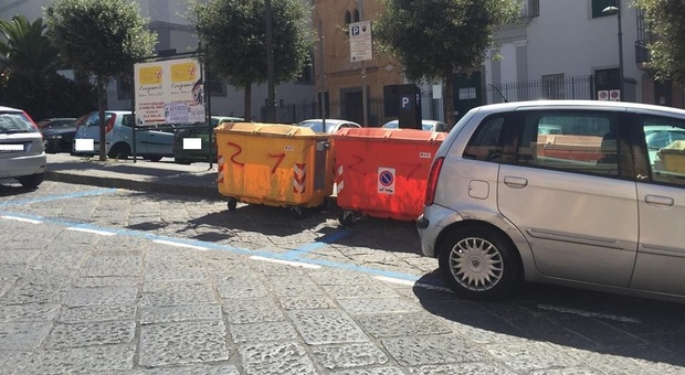 Lo strano caso della sosta auto: strisce blu sui cassonetti dei rifiuti