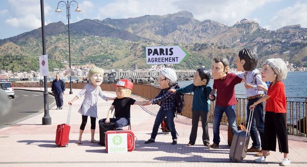 Flash mob di Oxfam a Taormina con le maschere dei 7 Grandi. Striscioni di Greenpeace in spiaggia