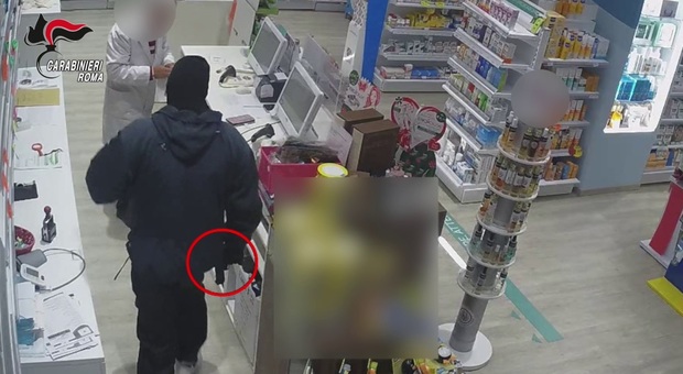Le immagini della telecamera di sorveglianza riprendono uno dei rapinatori che minaccia il farmacista