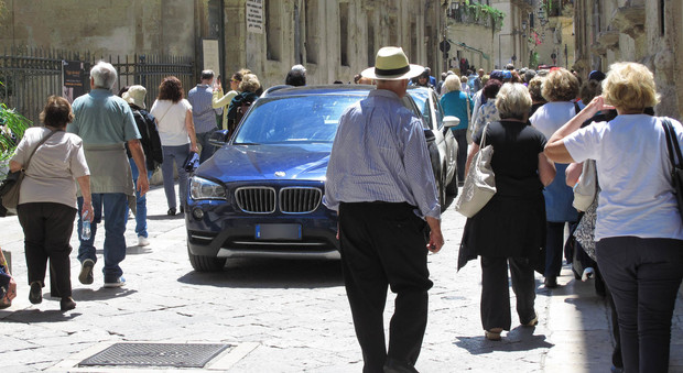 Turisti a spasso in città tra le auto