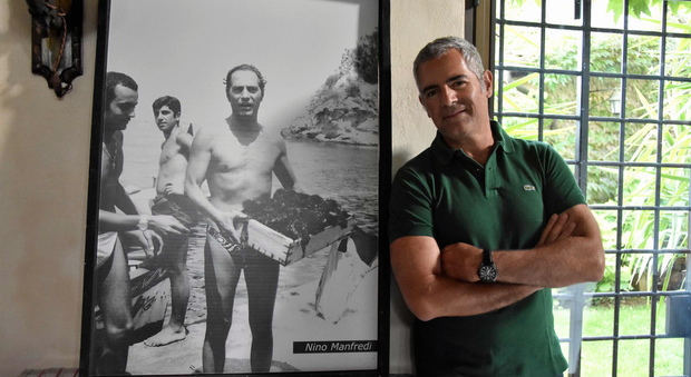 Luca Manfredi accanto a una foto del padre, nel suo casale in Umbria