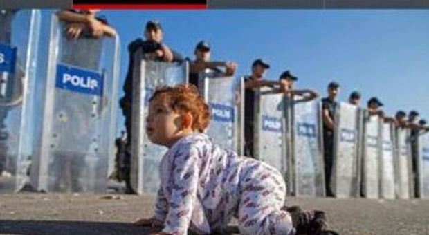 Migranti, baby-profuga siriana gattona davanti alla polizia schierata: la foto fa il giro del Web