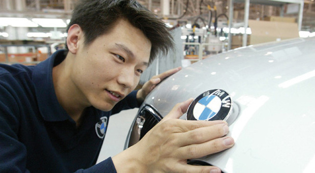 Un operaio cinese applica il logo ad una BMW prodotta nel grande paese orientale
