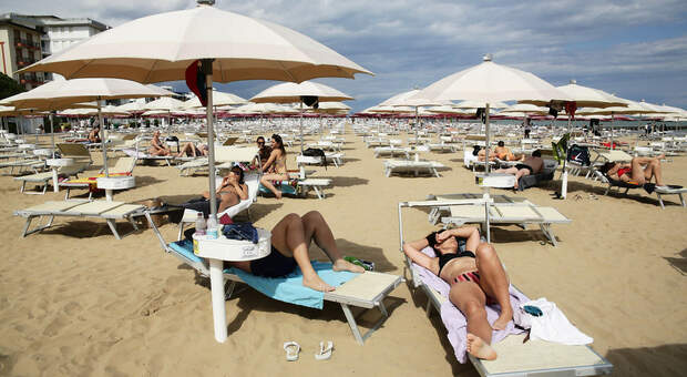 Alcune persone in spiaggia a Jesolo sul lettino e sotto all'ombrellone